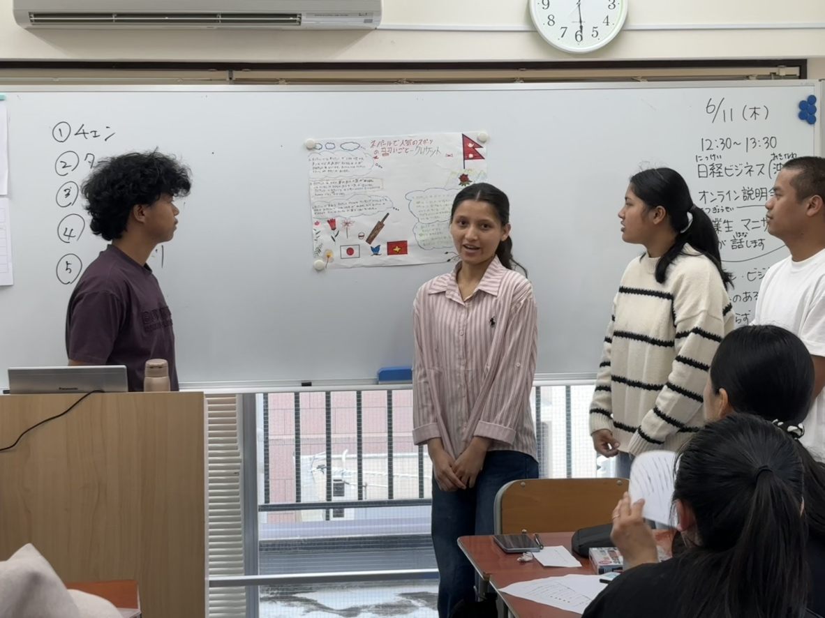 教室で学生の発表を見守る講師